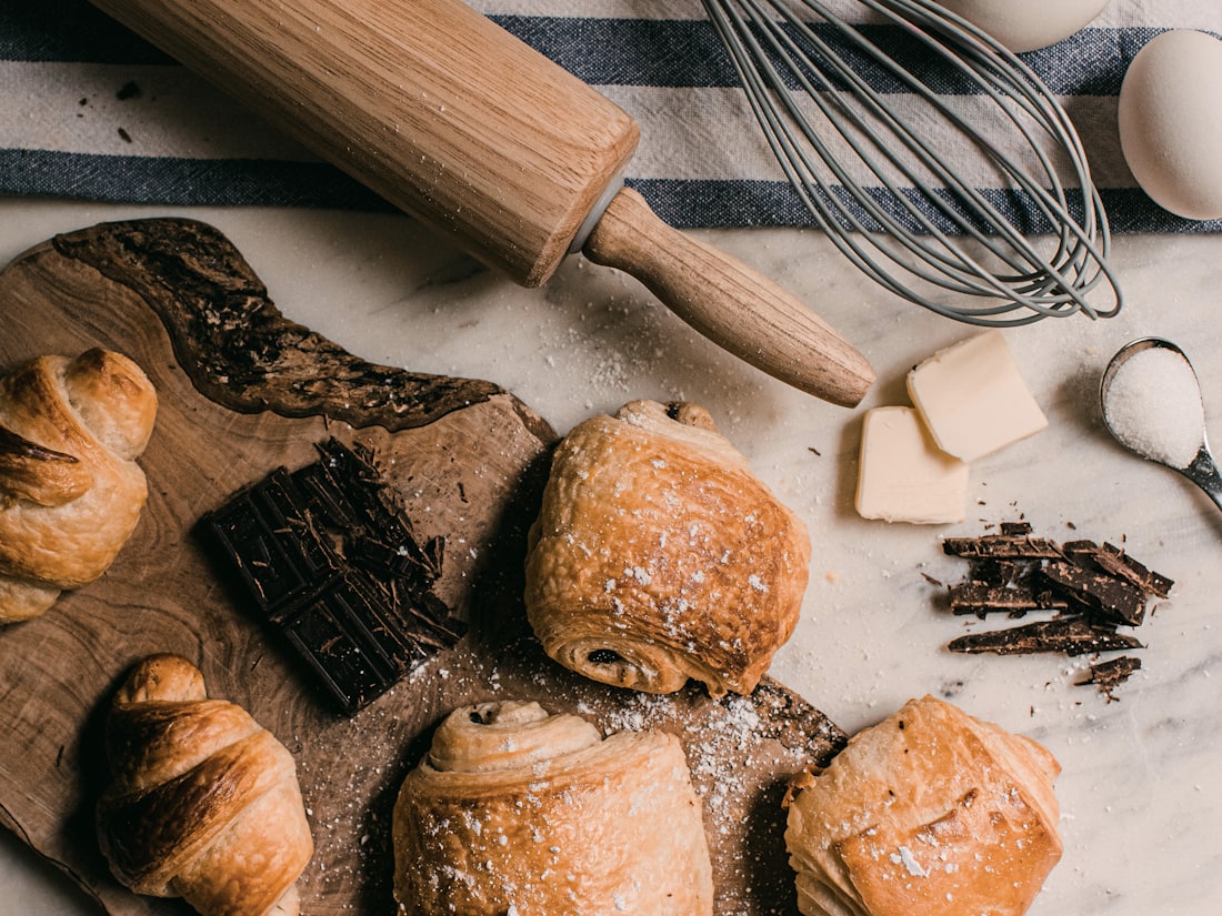 A baker's marble bench dusted with flour, fresh rolls and a rolling pin