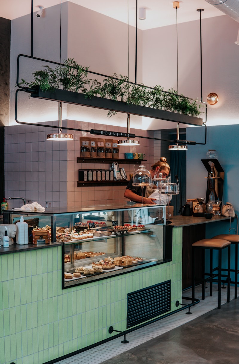 Bright modern bakery interior with sage-green tiles and a pastry counter