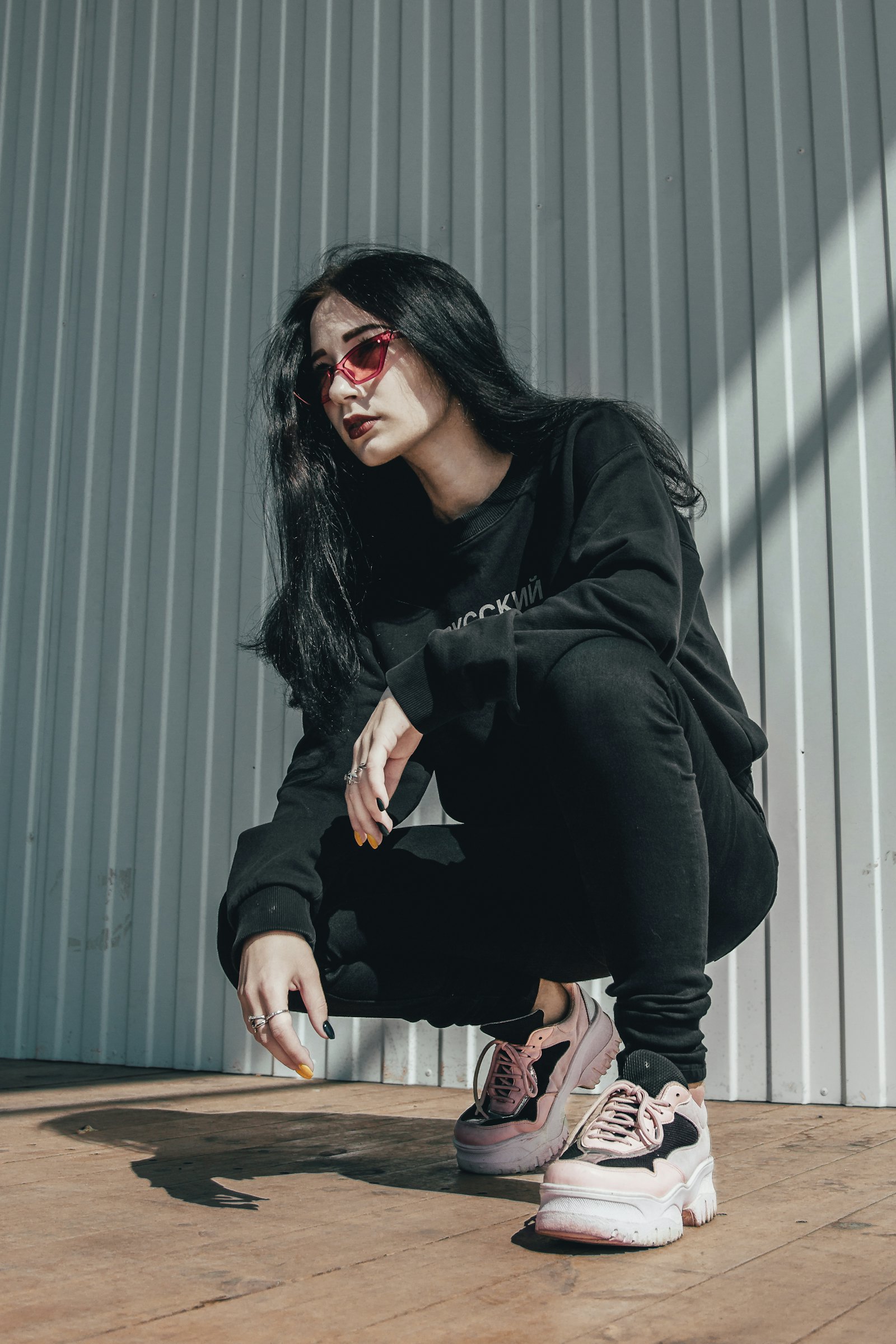 Streetwear model crouching in a heavyweight hoodie against corrugated steel