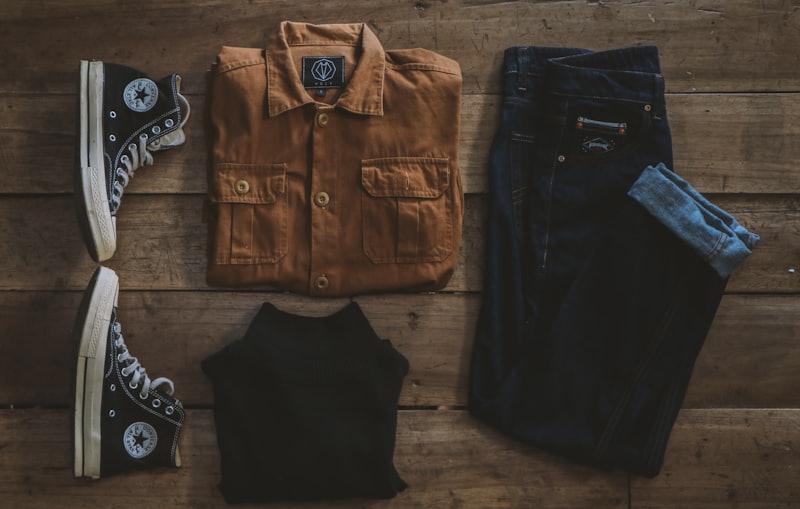 Field overshirt, denim and sneakers styled flat on weathered wood