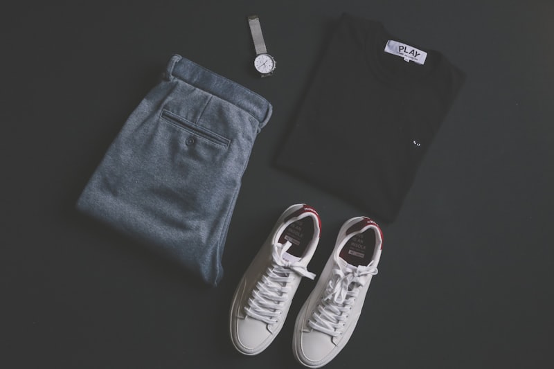 Tapered trousers folded with white court sneakers on charcoal