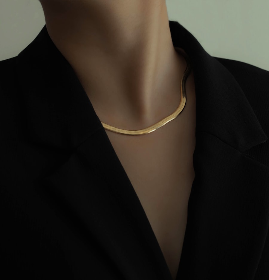 A slim gold chain against a dark tailored blazer