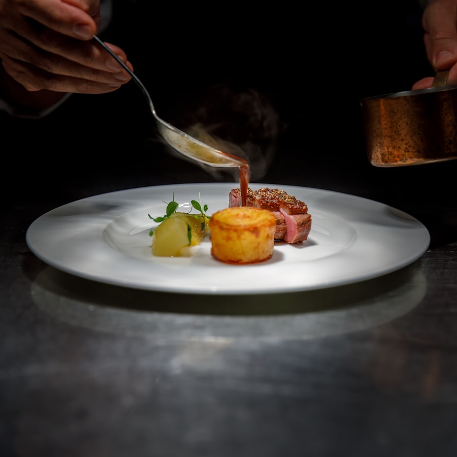 A chef finishing a plated fine dining dish under a single spotlight