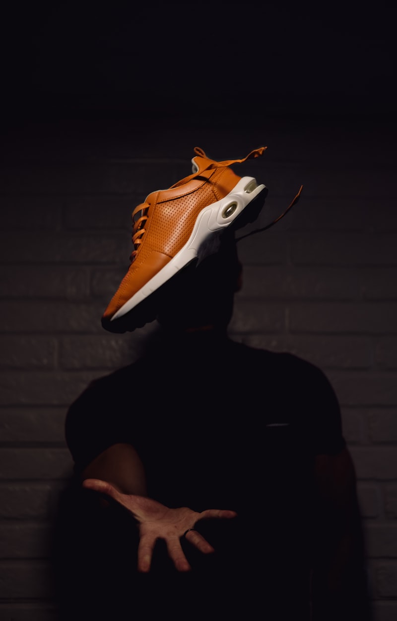 VOLTA orange sneaker held in a dark moody studio