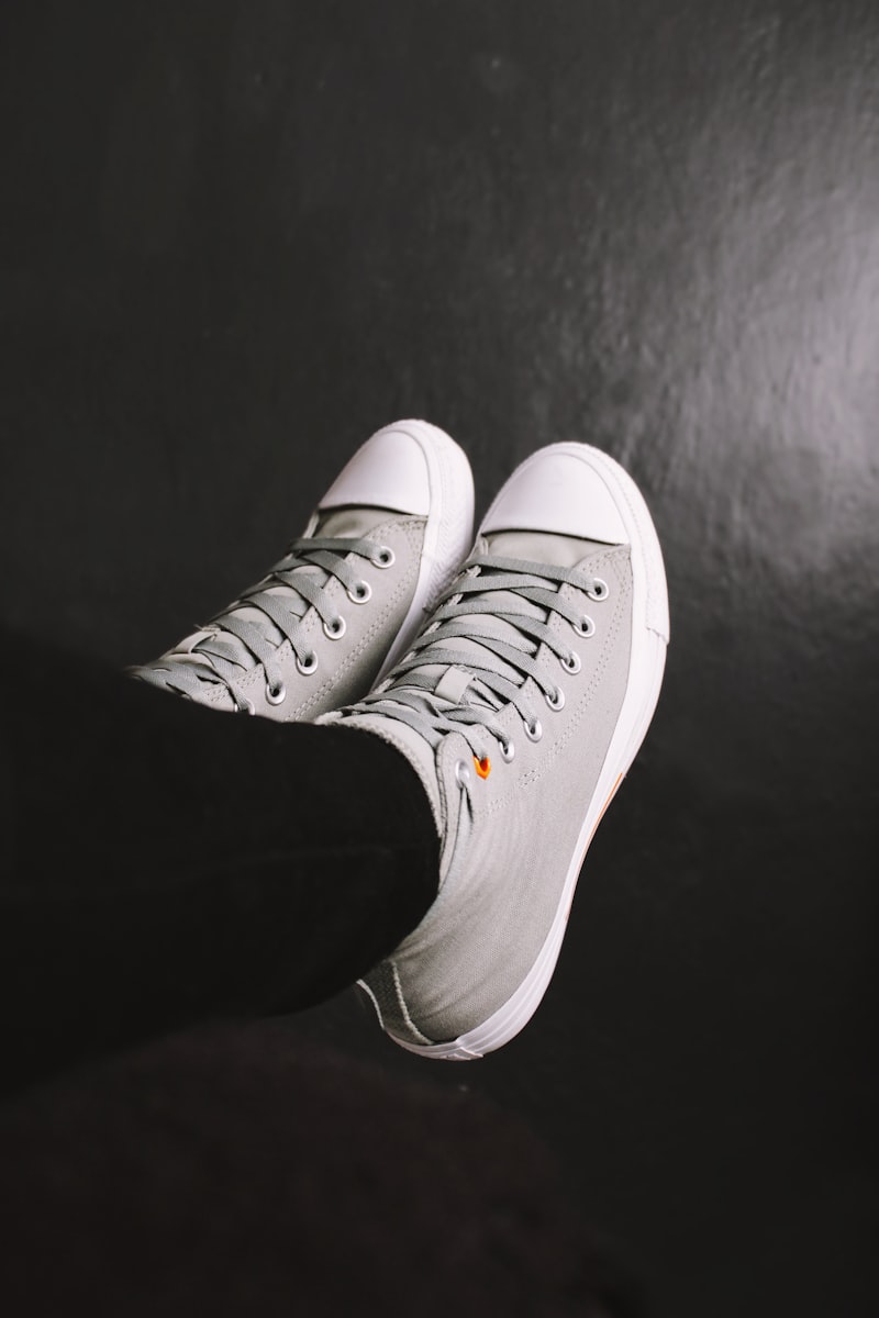 Two white VOLTA sneakers on a dark studio floor